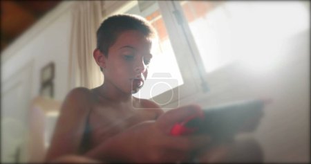 Photo for Child holding video-game gadget playing online tournament from home - Royalty Free Image