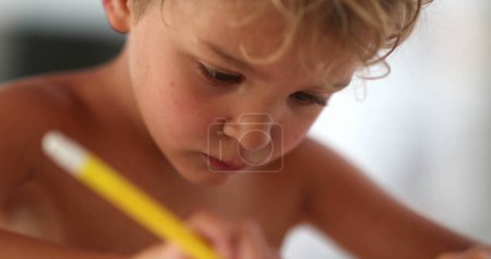 Foto de Dibujo a mano infantil sobre papel. Crianza artística concentrada del cabrito con la pluma del color - Imagen libre de derechos