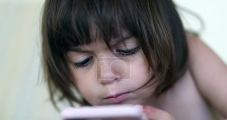 Foto de Bebé niña mirando el dispositivo de teléfono inteligente. Niño pequeño sosteniendo el teléfono celular - Imagen libre de derechos