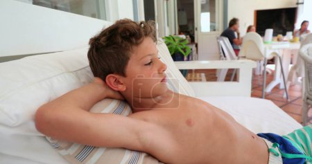 Photo for Pensive child in sofa thinking. Young boy lying on couch - Royalty Free Image