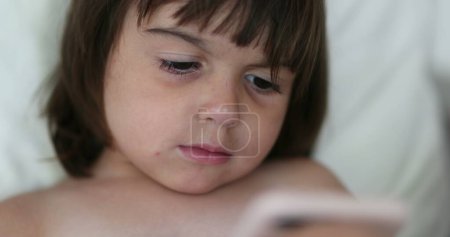 Foto de Cara de niña absorbida por el contenido en línea en el teléfono inteligente - Imagen libre de derechos