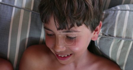 Téléchargez les photos : Enfants heureux jouant jeu en ligne avec tablette à la maison assis sur le canapé - en image libre de droit