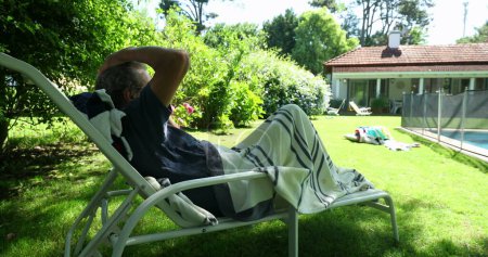 Photo for Senior older man relaxing in home backyard garden. Retired man resting lying down - Royalty Free Image