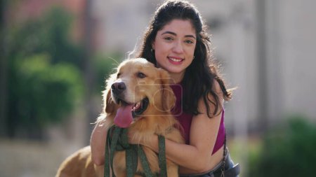 Photo for One young woman posing for camera with her Golden Retriever Dog at park during sunny day - Royalty Free Image