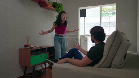 Foto de Pareja discutiendo la relación. Novia molesta discutiendo con su novio sentado en el sofá - Imagen libre de derechos