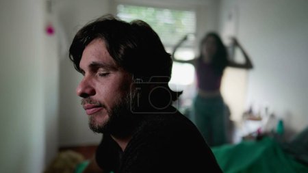 Photo for Stressed man in foreground while listening to screaming girlfriend standing in background. Boyfriend feeling mental pressure during relationship in crisis - Royalty Free Image