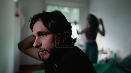 Photo for Stressed man in foreground while listening to screaming girlfriend standing in background. Boyfriend feeling mental pressure during relationship in crisis - Royalty Free Image