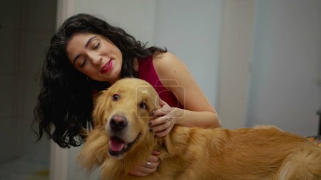 Téléchargez les photos : Femme partageant un moment chaleureux avec son cher Golden Retriever Pet à la maison. Propriétaire aimante embrassant son compagnon canin - en image libre de droit