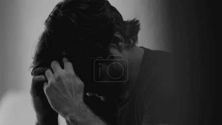 Photo for Dramatic depressed young man suffering from emotional pain. Somber closeup face of a male person in 30s feeling sadness and lost in monochromatic black and white - Royalty Free Image
