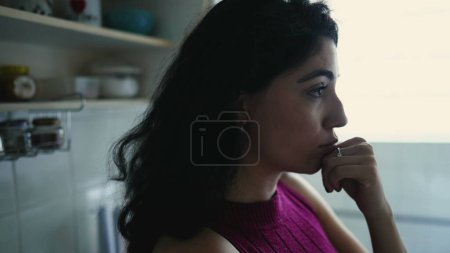 Photo for Contemplative woman lost in thought, standing alone in kitchen. Reflective person pondering life's choices in candid moment - Royalty Free Image