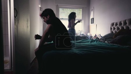 Photo for Couple Arguing and Fighting. Man feeling pressure by Female Partner. girlfriend in background discussing relationship while depressed man sits by the bedside feeling frustration - Royalty Free Image