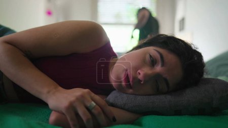 Photo for Relationship in crisis. Dismissive woman lying in bed rolling eyes while listening to upset husband gesturing with his body in the background - Royalty Free Image