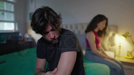 Foto de Pareja infeliz sintiéndose desconectados el uno del otro. Hombre y mujer sentados en la cama ignorándose unos a otros - Imagen libre de derechos