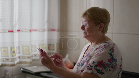 Photo for Senior woman using cellphone at home. Older lady typing message on phone device, elderly person using modern technology - Royalty Free Image