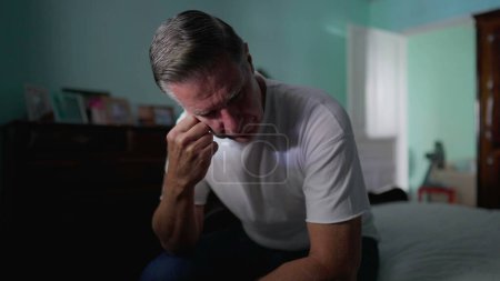 Photo for Stressed Middle-Aged Man Feeling Anxiety, Sitting by Bedside Depicting Mental Struggle and Preoccupation, suffering in quiet despair alone - Royalty Free Image