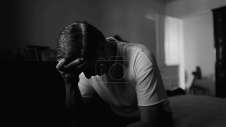 Foto de Representación monocromática del hombre de mediana edad cubriendo la cara con vergüenza, mostrando desesperación y soledad en una escena dramática en blanco y negro - Imagen libre de derechos