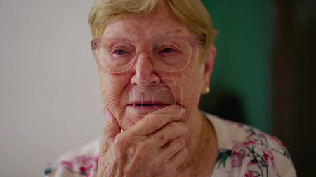 Téléchargez les photos : Pensive femme âgée réfléchissant à la solution. Une personne âgée caucasienne dans les années 80 contemplant l'émotion en gros plan visage avec la main dans la pensée menton - en image libre de droit