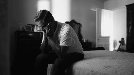 Téléchargez les photos : Homme âgé souffrant de désespoir tranquille aux prises avec des problèmes mentaux dans la chambre à coucher de la maison en noir et blanc monochrome - en image libre de droit