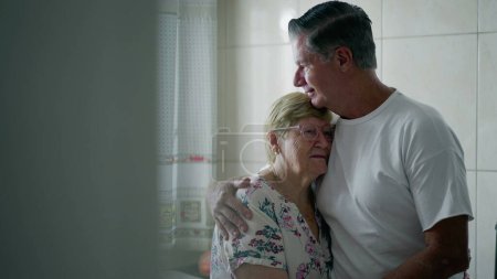Téléchargez les photos : Moment franc d'un fils plus âgé embrassant une mère âgée à la maison, d'une affection familiale authentique et de soins prodigués - en image libre de droit