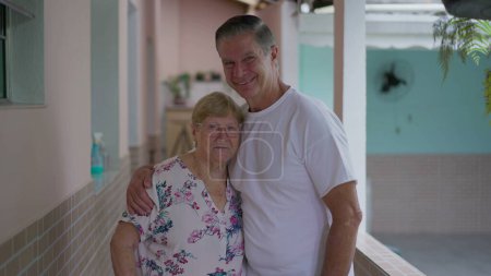 Photo for Adult son kissing senior mother in forehead while posing together, elderly care-taking with arm around elderly parent - Royalty Free Image