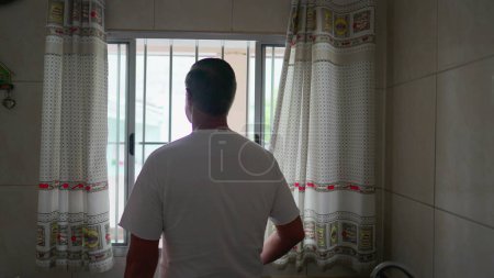 Téléchargez les photos : Retour de la personne ouvrant rideau de cuisine le matin, homme commençant la journée et regardant dehors à la lumière du jour vue - en image libre de droit