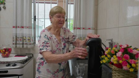 Foto de Mujer anciana sirviendo café y dándole taza a alguien que está en la cocina. estilo de vida doméstico auténtica vejez de la persona mayor presionando termos - Imagen libre de derechos