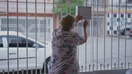 Téléchargez les photos : Femme âgée vérifiant le courrier à la maison avant, personne âgée ouvrant la boîte en métal, routine domestique quotidienne - en image libre de droit