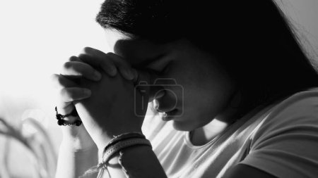 Téléchargez les photos : Dévotion dramatique de la jeune femme priant Dieu en noir et blanc monochrome. Spirituel contemplatif adulte fille dans les années 20 - en image libre de droit