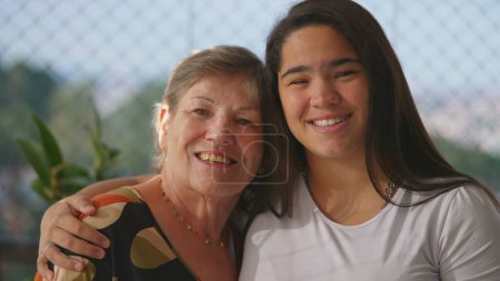Photo for Embracing Generations Close-Up Smiling Faces of Diverse Asian Granddaughter with Arms Around Caucasian Grandmother - Royalty Free Image
