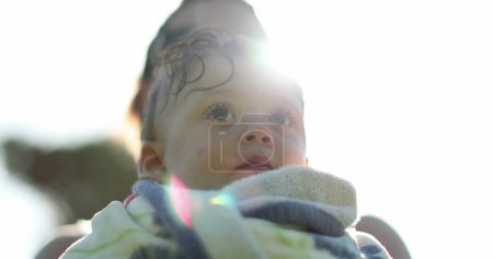 Photo for Toddler after pool. Mother holding baby outside in sunlight lens-flare after swimming - Royalty Free Image