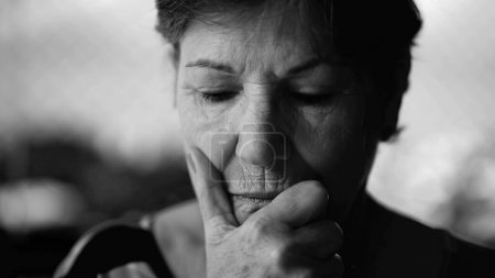 Photo for Dramatic pensive older woman in deep thought with hand in chin in monochromatic black and white - Royalty Free Image