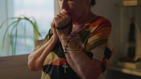 Téléchargez les photos : Religieuse catholique plus âgée Prier Rosaire à la maison dans une profonde contemplation. Personnes âgées ayant l'ESPOIR et la Foi - en image libre de droit