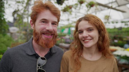Téléchargez les photos : Couple rousse debout à l'intérieur de l'environnement vert, portraits de heureux hommes et femmes aux cheveux rouges dans la trentaine - en image libre de droit