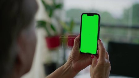 Téléchargez les photos : Main de personne âgée tenant smartphone avec écran vert clé Chroma. Personne âgée regardant l'écran du téléphone - en image libre de droit