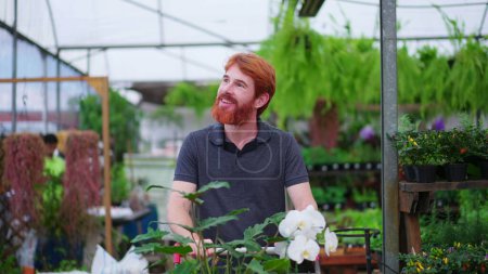 Photo for Happy Young Man with Shopping Cart exploring Aisle in Horticulture Store. Male Customer Shopping for Plants at Local Garden Shop - Royalty Free Image