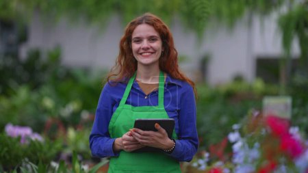 Photo for Portrait of a female florist employee staff holding tablet standing inside Plant Store smiling at camera - Royalty Free Image
