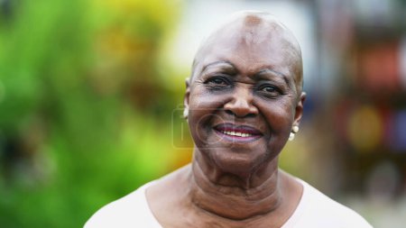 Foto de Retrato de una mujer mayor afroamericana girando cabeza a cámara sonriendo. Primer plano de una mujer mayor brasileña negra con expresión alegre - Imagen libre de derechos