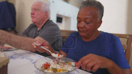 Téléchargez les photos : Femme âgée mangeant le déjeuner à l'heure du repas, un groupe de personnes âgées diverses au cours du repas. Gros plan d'une femme plus âgée brésilienne mange de la nourriture - en image libre de droit
