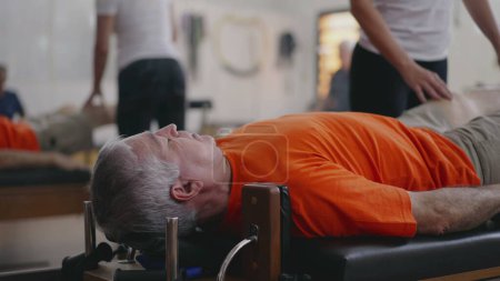 Téléchargez les photos : Physiothérapeute aidant l'homme âgé dans Pilates Machine Use _ Promoting Bien-être et force dans la vieillesse - en image libre de droit