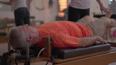 Foto de Sesión de fisioterapia bajo la guía de un entrenador de pilates, fortaleciendo las piernas del paciente con la máquina - Imagen libre de derechos