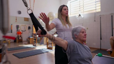 Foto de Mujer mayor participando en una sesión de pilates con entrenadora, enfatizando la salud de la columna vertebral en la rutina de ejercicios de vejez - Imagen libre de derechos