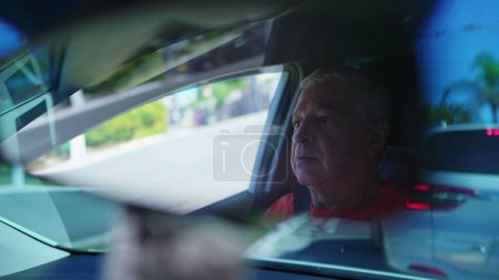 Foto de Un hombre mayor atrapado en el tráfico en las calles de la ciudad visto a través del espejo retrovisor. Conductor mayor detenido detrás de los vehículos - Imagen libre de derechos