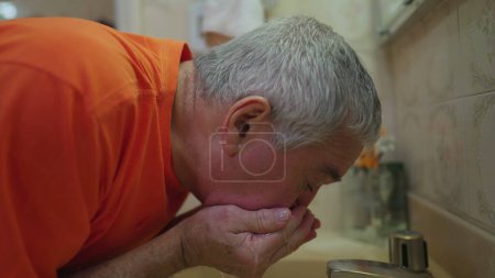 Foto de Hombre mayor lavando cara por lavabo de baño durante el estilo de vida de rutina de la mañana - Imagen libre de derechos