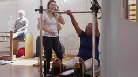 Foto de Ejercicio para personas mayores en Pilates Group Class, una mujer negra que usa la máquina para fortalecer el cuerpo. Estilo de vida de entrenamiento de vejez - Imagen libre de derechos