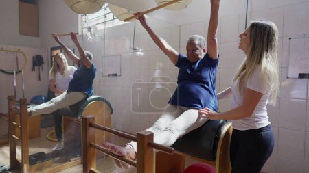 Foto de Una mujer negra mayor que participa en el ejercicio de rehabilitación fisioterapéutica bajo pilates femeninos Instructor _ s Guidance - Imagen libre de derechos