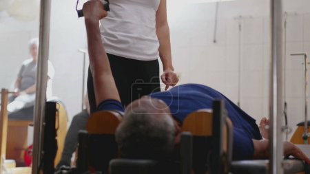 Foto de Instructor de Pilates femenino entrenando a una mujer negra para usar la máquina de pilates en el estudio de fisioterapia - Imagen libre de derechos