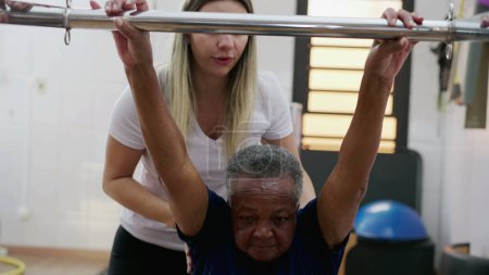 Téléchargez les photos : Entraîneur de Pilates féminin aidant une femme âgée noire à utiliser la machine, la routine d'entraînement de vieillesse, la flexibilité et le renforcement du corps - en image libre de droit