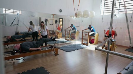 Photo for Group of elderly people exercising in Pilates Studio. old age workout routine. Female coach orienting seniors to strengthen and stretch body - Royalty Free Image