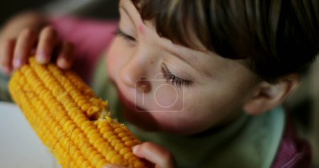 Foto de El chico come maíz un niño pequeño come comida - Imagen libre de derechos