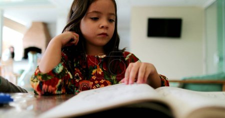 Photo for Little girl turning papers from drawing book child picking what page to draw - Royalty Free Image